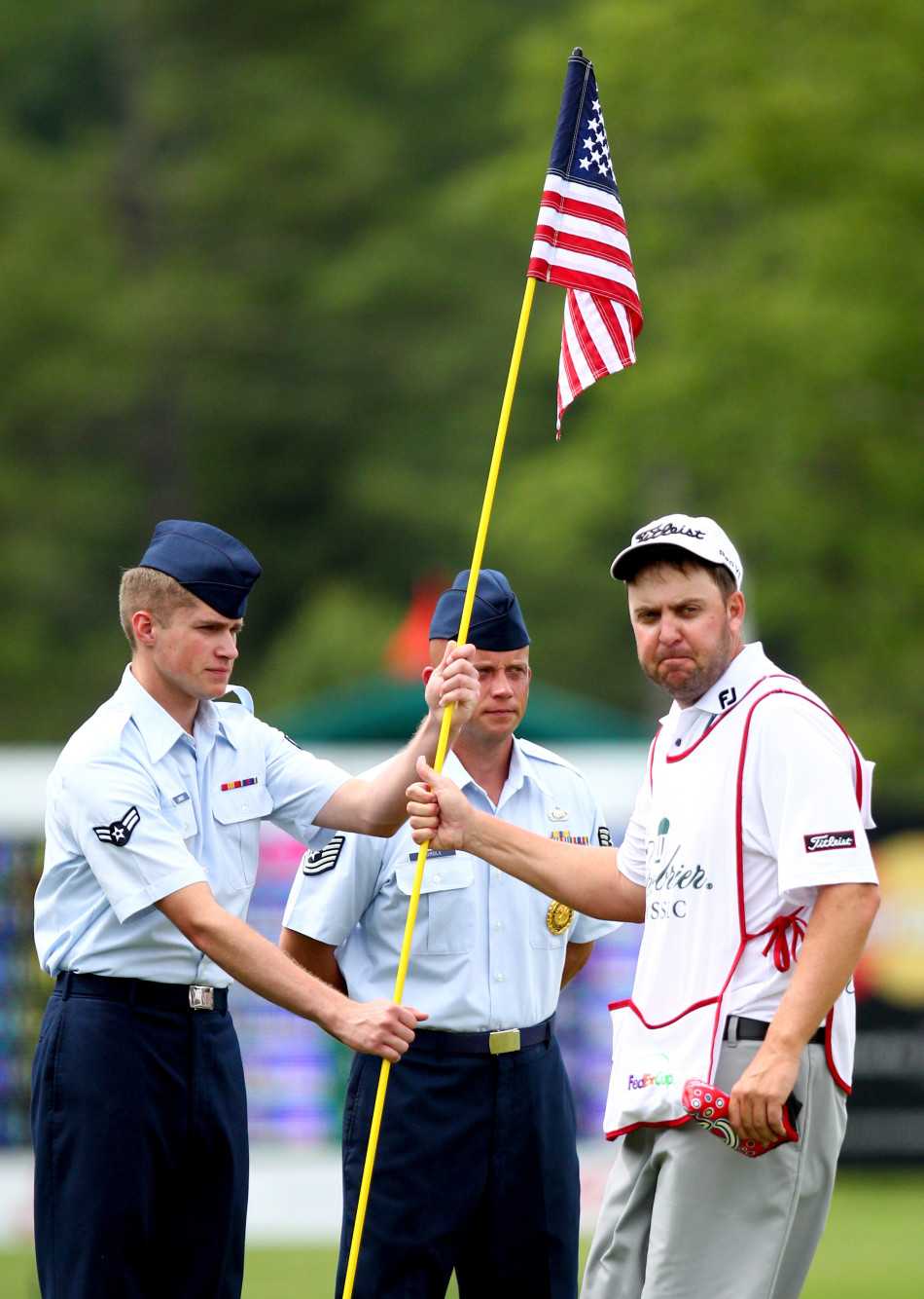 身着传统制服的卫兵面向美国国旗立正，庄严地行举手礼，果岭的背景让这一致敬显得独特而神圣。