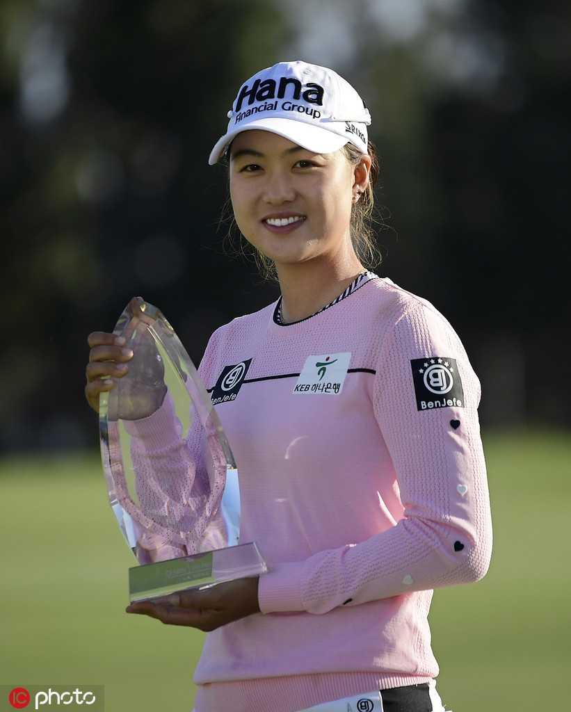 李旻智手捧冠军奖杯，在第十八洞果岭旁露出灿烂笑容，庆祝职业生涯第五个LPGA冠军。