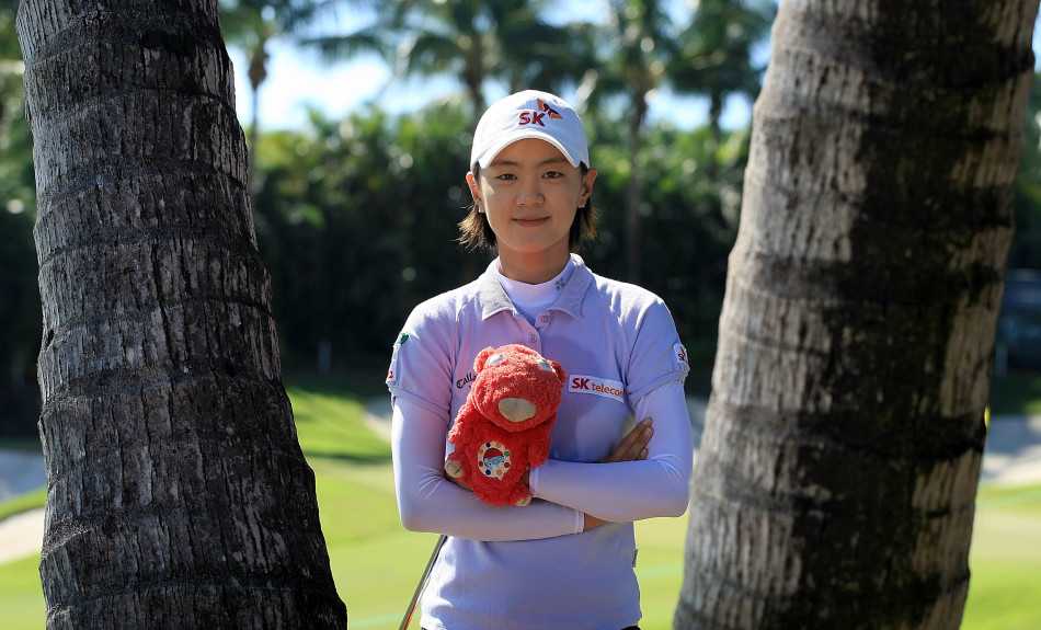 崔罗莲在果岭边专注地凝视远方，仿佛在计算着下一杆的精准路线，微风轻拂她的发丝。