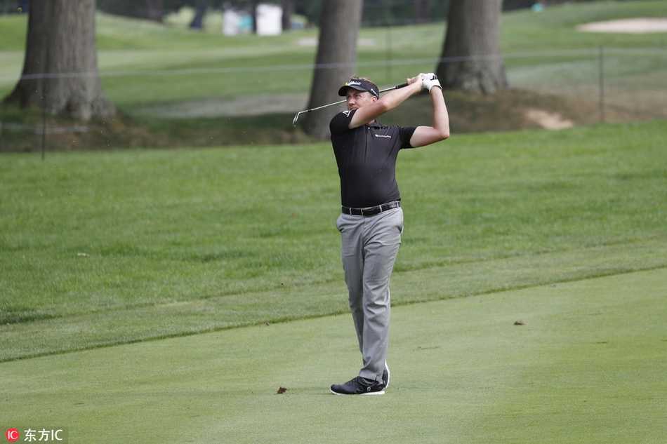 老虎伍兹凝神注视小白球，在火石球场翠绿果岭上策划关键一击