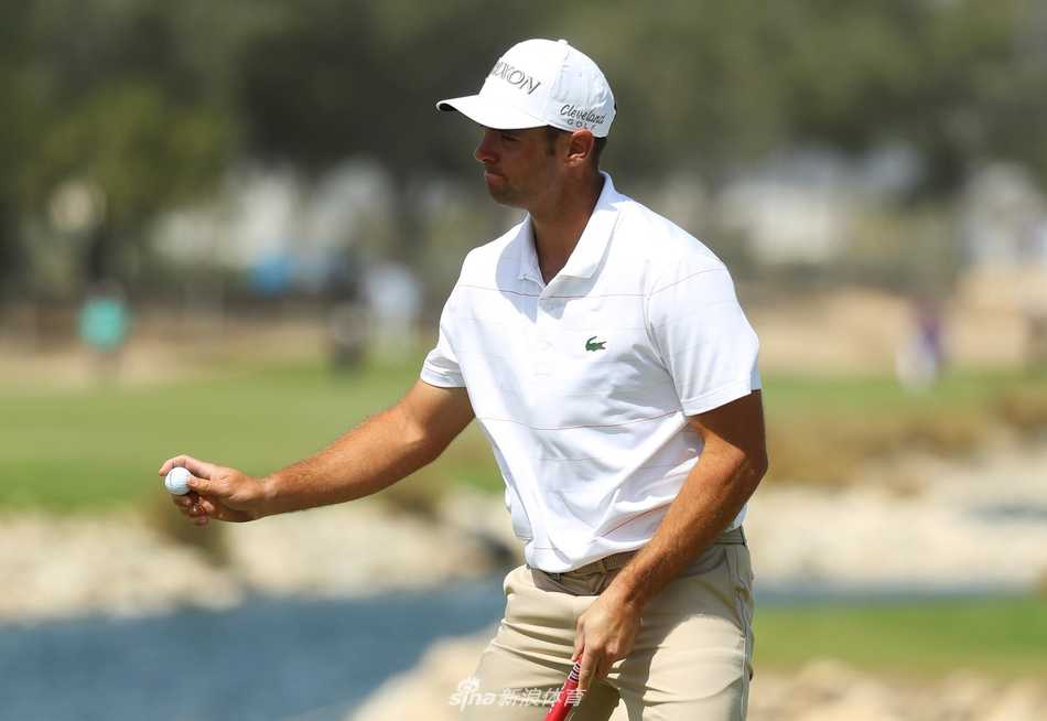 比赛因大风一度中断，球员和球童在沙坑旁等待，长草在强风中摇曳。