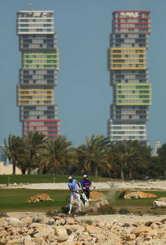 球童为球员细致地擦拭高尔夫球，两人在风中专注地讨论下一杆的策略。