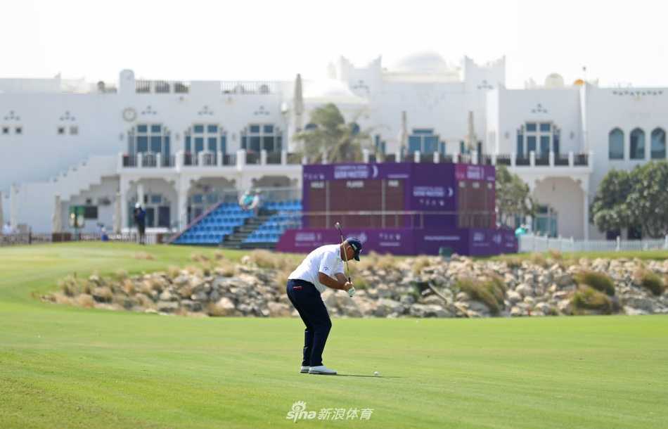 夕阳西下，球员完成推击后与球童一起走过桥梁，剪影映衬在多哈的城市天际线前。