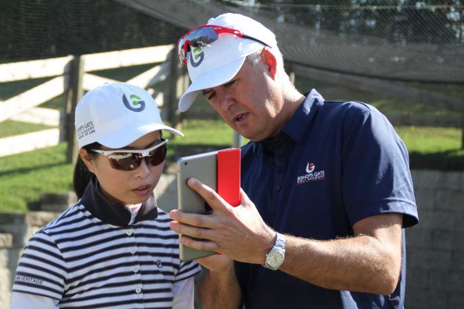 教练Scott正使用辅助器材引导学员的上杆路径，一根轻质训练棒沿着理想的平面缓慢移动，重塑肌肉记忆