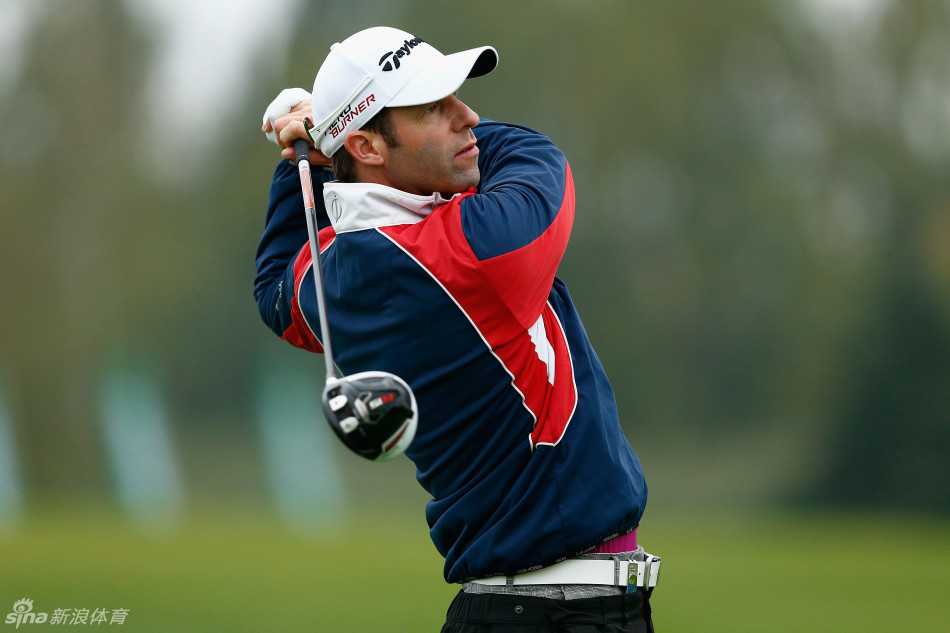 布拉德利·德雷奇与他的球童在球道上并肩站立，两人正低声讨论下一杆的进攻策略，球童手中的码数本和专注的神情是团队协作的缩影。