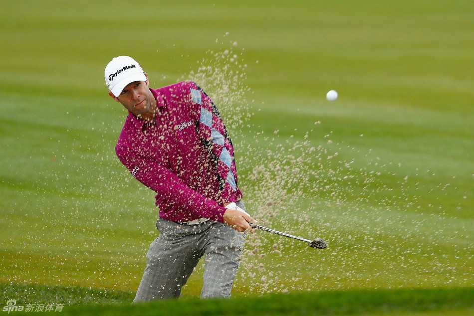 威尔士球手布拉德利·德雷奇正全神贯注于一次果岭边的沙坑救球，他双腿稳稳扎入沙中，目光锁定小球，正准备挥杆将球击向洞杯。