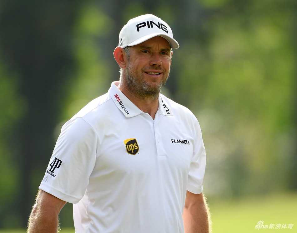 马来西亚锦标赛观众簇拥在果岭周围，凝神观看球员推杆，现场气氛紧张而热烈。