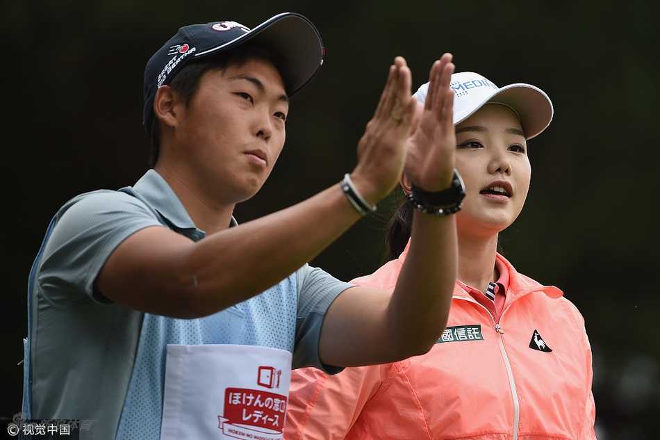 石昱婷与球童并肩前行，两人正专注地商讨下一杆的策略，体现了团队间的默契合作