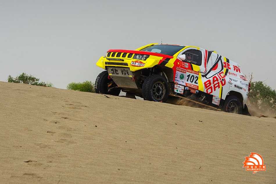 赛车在金色沙海中犁出深痕，如同一叶孤舟勇敢地划破无尽沙海的宁静，奔赴远方地平线。