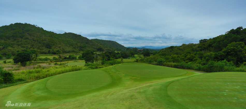 青翠球道蜿蜒于群山环抱之中，远方峰峦叠嶂，清晰如黛，宛若一幅宁静的山水长卷