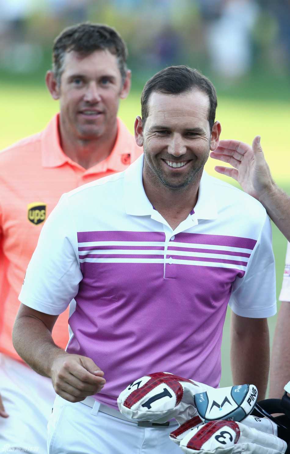 加西亚弯腰耐心指导一位小球迷握杆，笑容温暖，画面充满传承与关怀的动人瞬间。