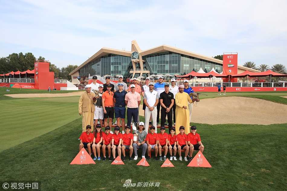 卫冕冠军托米-弗利特伍德手持球杆，于阿布扎比灿烂的阳光下展露自信微笑，身后是球场标志性的景观