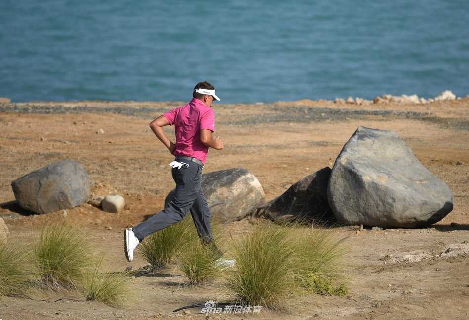 工作人员正在帮助布鲁克斯·科普卡移开击球路径上的石头，科普卡在一旁观察准备。