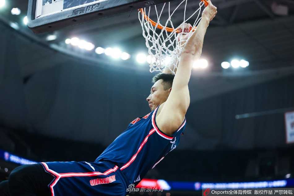 广东队射手杜润旺在三分线外出手瞬间，篮球刚刚离开指尖，画出一道优美的弧线，他身后的上海队防守球员伸手干扰却已鞭长莫及，背景板是模糊而喧嚣的观众席。