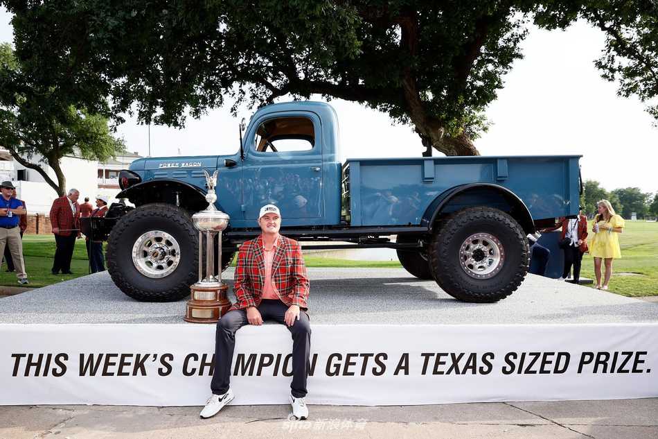 简森·科克拉克身披传统的冠军格呢夹克，与复古的1946年款施瓦布冠军卡车合影，历史与现代在此交汇。