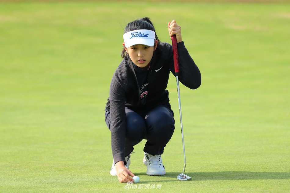 在球场水景边，她凝神准备推杆，水面倒影与静谧氛围凸显了高尔夫运动所需的极致冷静