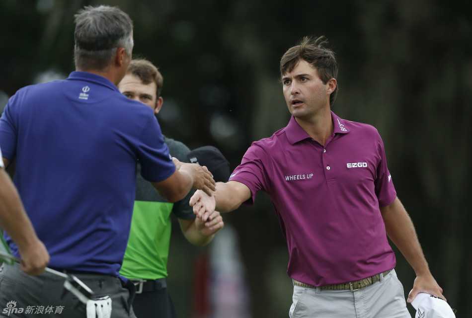 美国选手凯文·基斯纳在果岭边，与同组球员完成比赛后，面带微笑伸出手臂，进行一次彰显体育精神的友好握手。