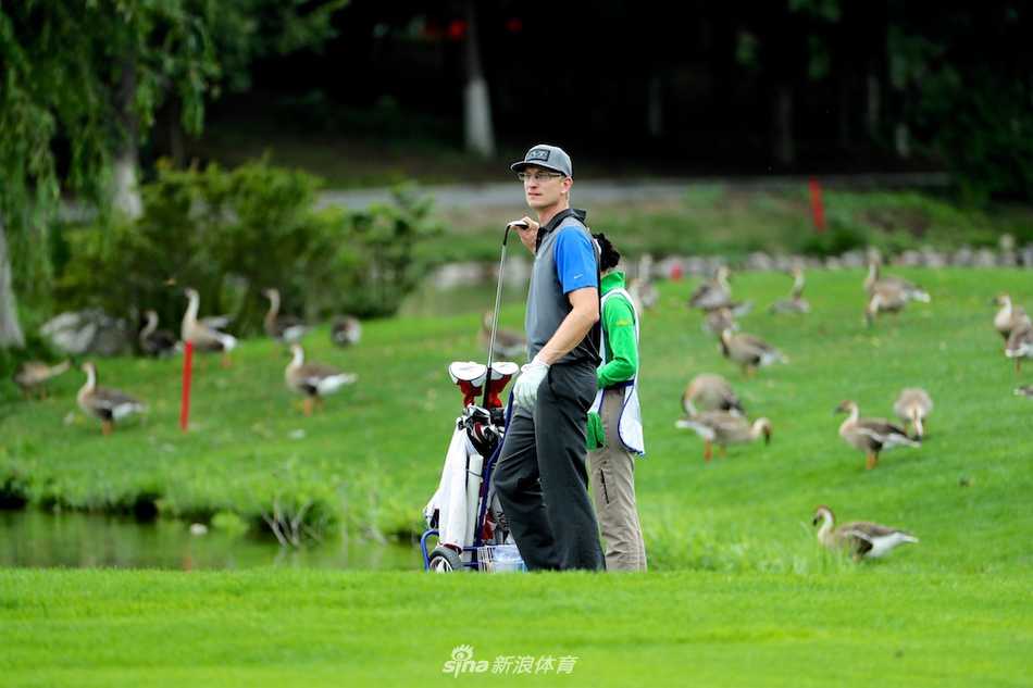 佘梓瀚与球童何绍庭在球道上并肩行走，侧身交流，展现了球员与球童之间默契无间的伙伴关系