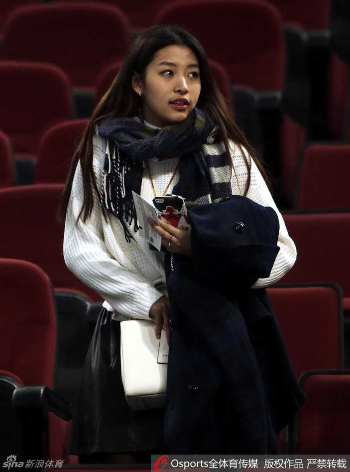 她专注地望向赛场方向，手中似乎还拿着助威的小道具，仿佛下一秒就要为心爱的球星呐喊助威。