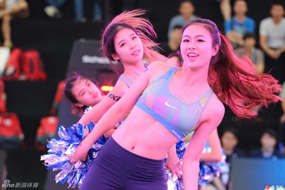 远景镜头下，多支啦啦队同时在赛场不同区域列队表演，她们动作整齐划一，绚丽的色彩与激烈的球场形成一幅充满活力的画卷。