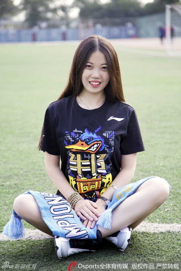 她将横幅高高举过头顶，修长的身姿在冬日的阳光下形成一道亮丽的风景线，灿烂的笑容仿佛能驱散一切严寒，只为传达对首钢队最炙热的支持。