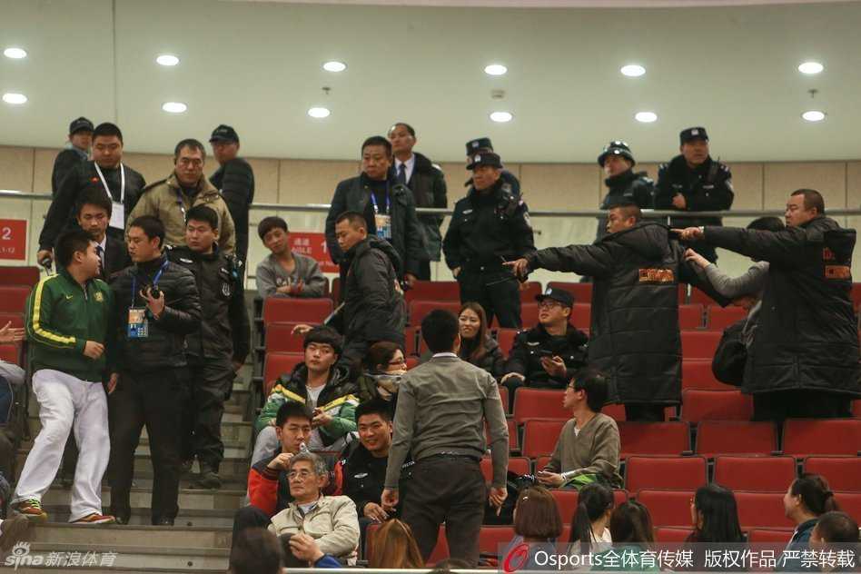 五棵松体育馆内人声鼎沸，但看台上紧张的气氛一触即发，部分球迷情绪激动地站起身，手势激烈地指向场地中央，周围的安保人员神情严峻，迅速向事发区域靠拢，试图在冲突升级前进行干预。