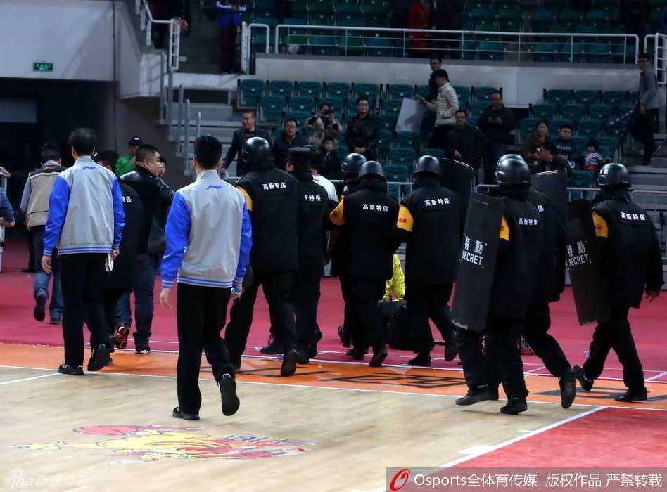 数名身穿黑色制服的安保人员紧密环绕，组成一道移动的人墙，将被护送的裁判员紧紧围在中间，他们的神情严肃而警惕，目光扫视着周围涌动的人群。