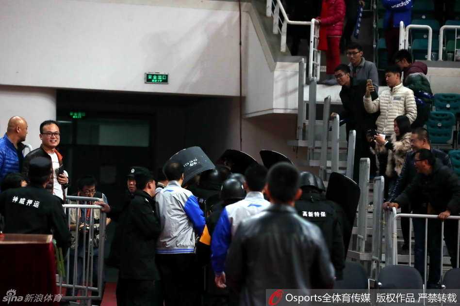 在一片喧嚣与混乱中，多名安保人员如临大敌，紧紧簇拥着裁判组，快速穿过通道，确保他们安全离开球场。