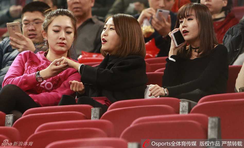 其中一位女友举起手机记录下这难忘的赛场时刻，背景是绿色的地板和模糊的观众身影，她要将这份为爱加油的记忆永久珍藏。