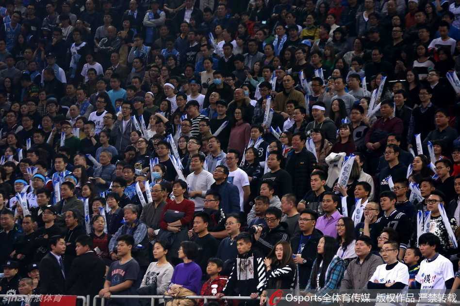 混乱的人群中，一名年幼的小球迷被父亲架在肩头，孩子稚嫩的脸上满是困惑与无措，伸出小手似乎想要触碰什么，与周围成人激动的情绪形成鲜明对比。