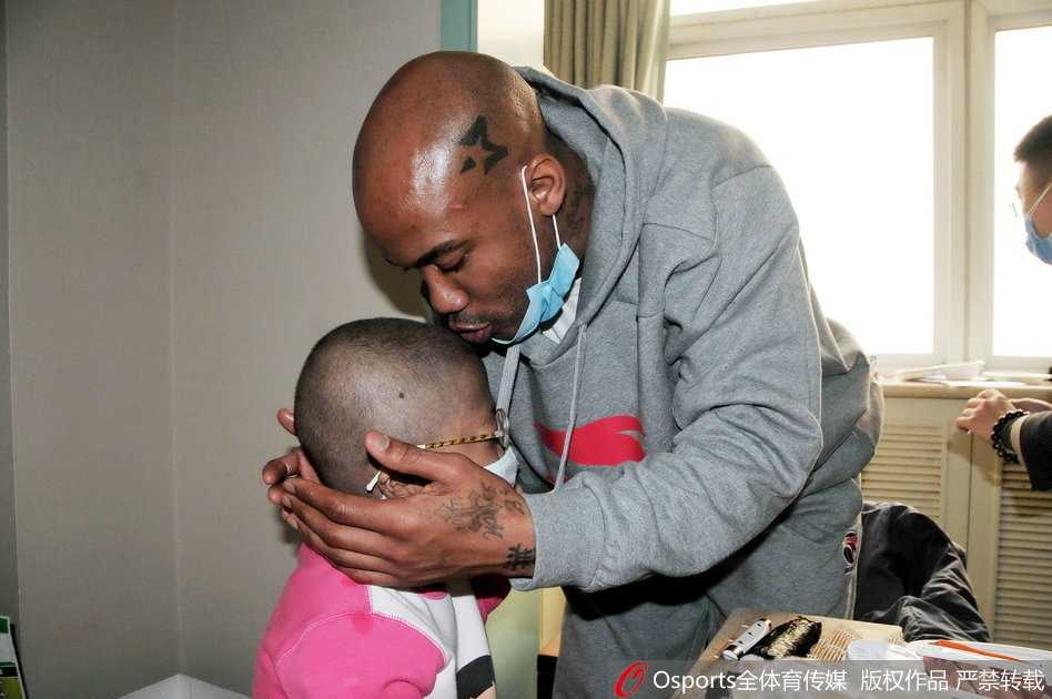 社区居委会门口，马布里戴着口罩与几位身穿工作服的社区大姐站在一起，他手里举着隔离期满证明，大家对着镜头一起竖起大拇指