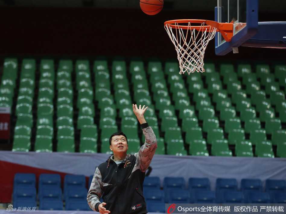 王治郅神情专注地持球准备示范，虽然身着便装，但持球的姿态依旧标准，仿佛瞬间回到了球员时代。