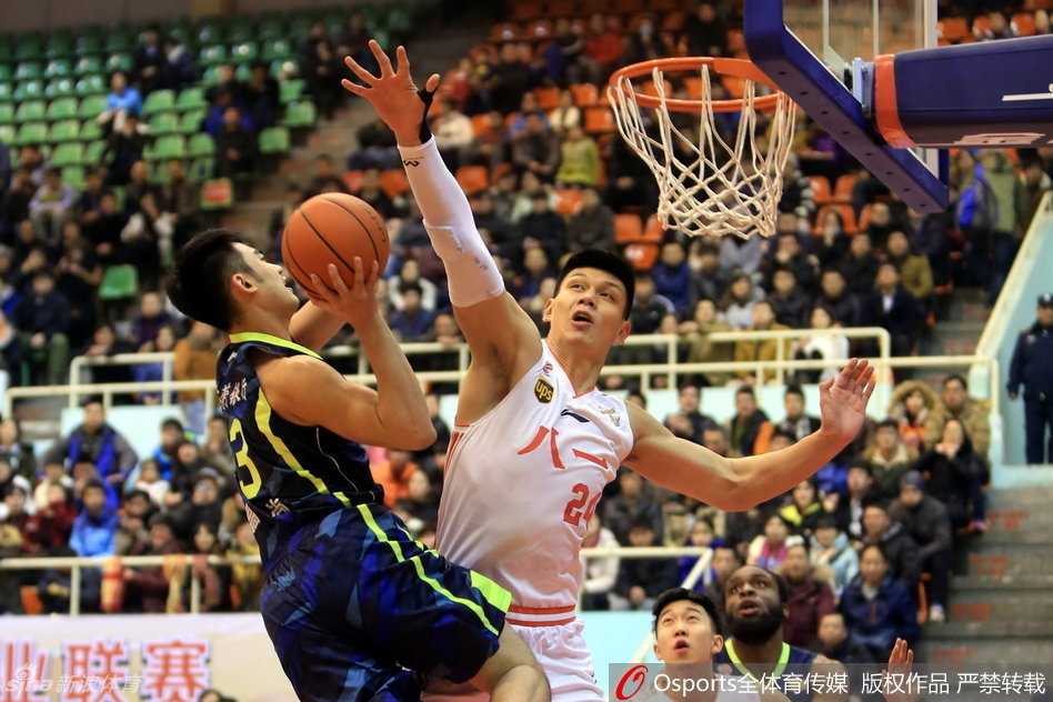 八一队主教练阿的江在场边神情严峻地给队员们布置战术，身后的比分牌显示着差距，他的眼神中既有对弟子的心疼也有对胜利的不甘。