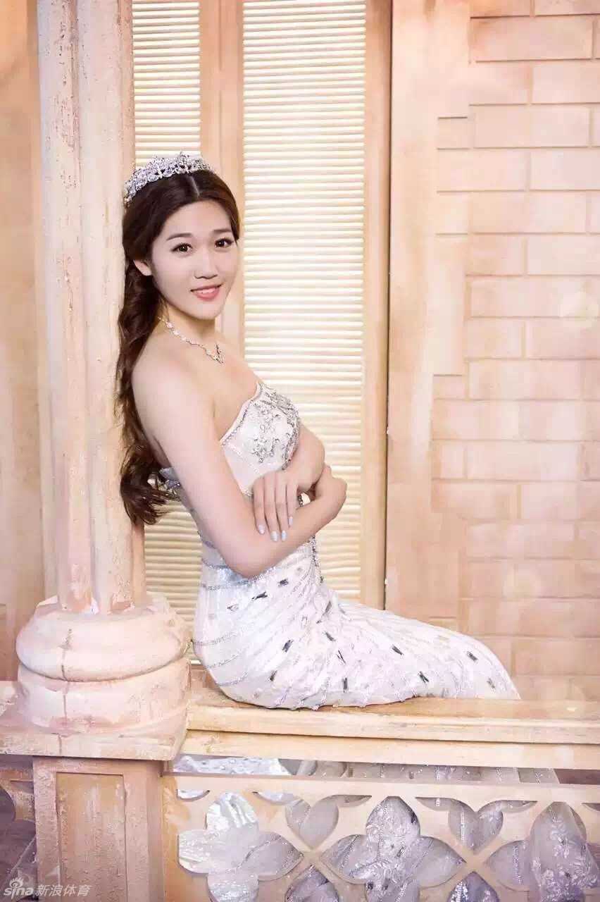 李莹身着一袭洁白婚纱，在海边礁石上优雅伫立，海风轻拂她的发丝，这位在赛场上以