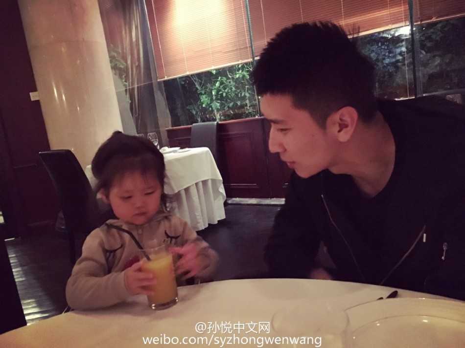 孙悦惬意地坐在遮阳伞下休息，小月亮则乖巧地坐在父亲身边，自己动手享受着美味的食物，孙悦的目光始终温柔地追随着女儿的一举一动，享受着这片刻的宁静与美好。