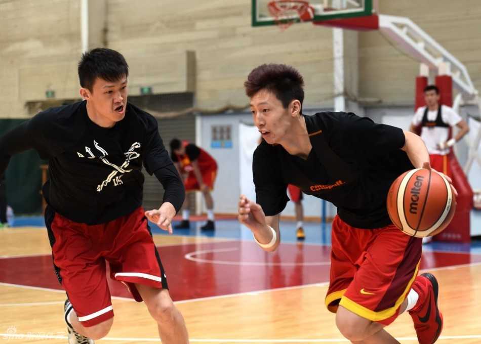 训练间隙，宫鲁鸣双手抱胸站在场边，神情专注地凝视着场上正在进行力量恢复的弟子们，夕阳的余晖透过高窗洒在他身上，映出一位老帅的坚守与期望。