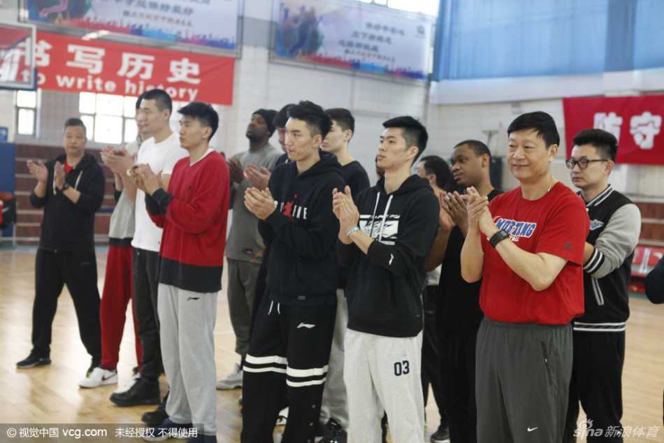新疆广汇男篮的球员们整齐列队，穿着标志性的蓝色训练服，李秋平指导站在队伍前方，队员们神情专注而坚毅，掌声在空旷的训练馆中回荡