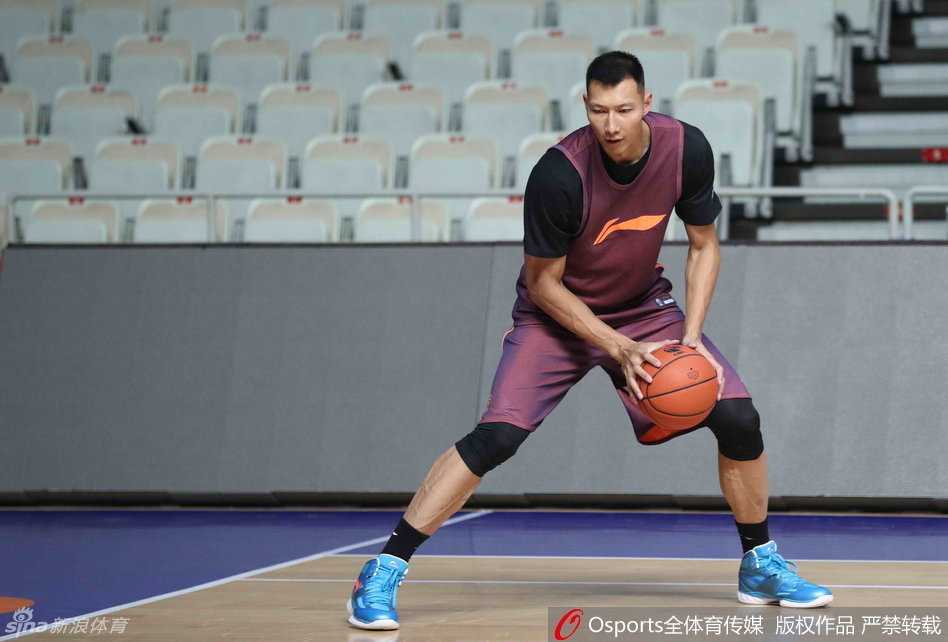 易建联低头凝视脚上的定制战靴，黑色的鞋面上点缀着金色细节，仿佛承载着新赛季的雄心，他正在拉伸腿部，为即将开始的对抗训练做着最后准备。