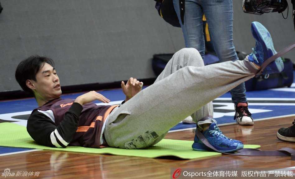 杨学增指导双手交叉抱在胸前，静静地站在场边注视着球员们的上篮训练，目光深邃而平和，仿佛整个球馆的节奏都尽在他的掌握之中