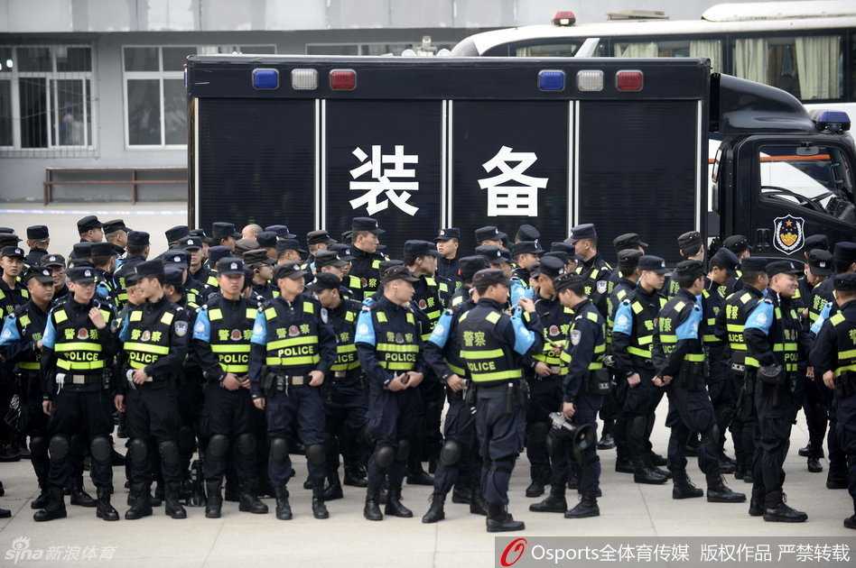 体育馆入场口，数名身穿统一制服的安保人员站成一排，他们手挽手形成一道人墙，有序地疏导着潮水般涌来的观赛球迷。