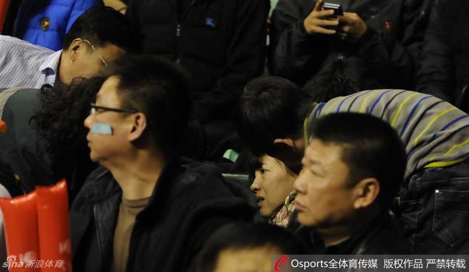 在众人的惊呼与帮助下，晕倒的女球迷在同伴的搀扶下艰难地试图撑起身体，但身体的极度不适让她的动作显得异常吃力。