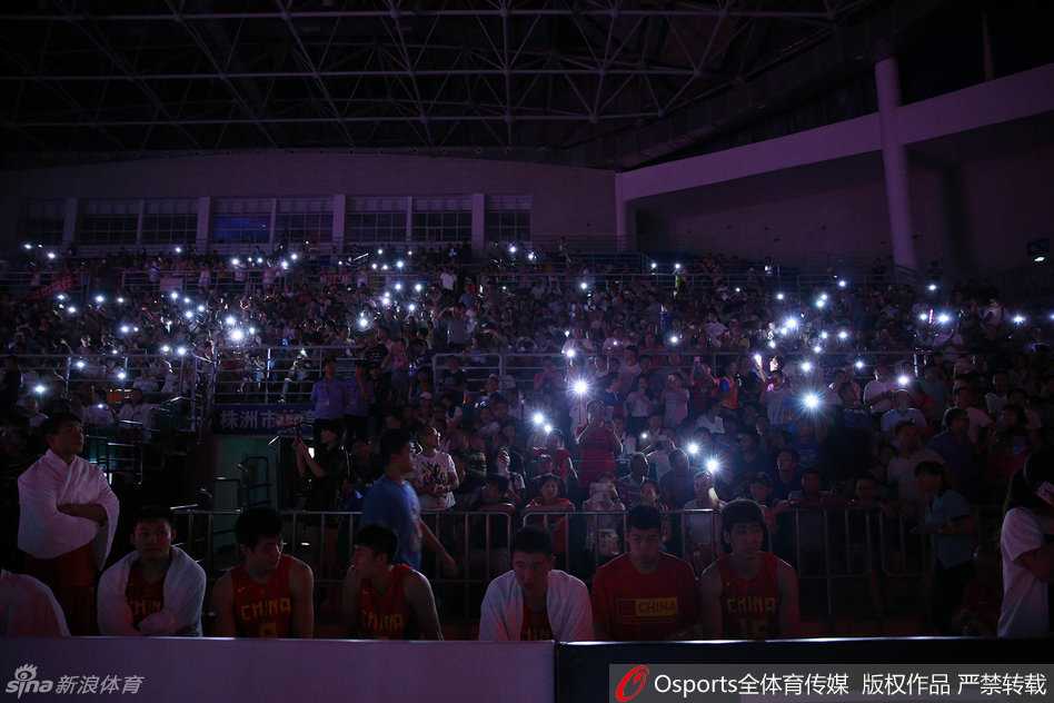 获胜后的国奥球员们聚拢在一起，脸上洋溢着灿烂的笑容，远处的看台上依旧有球迷亮着手机，仿佛要用光芒留住这难忘的胜利瞬间。