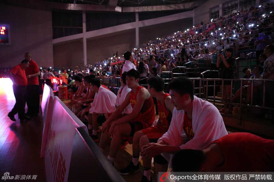 赛场全景图，明亮的灯光下是刚刚激战过的地板，而看台上星星点点的光芒尚未完全熄灭，记录下一场体育与温情交织的完美风暴。