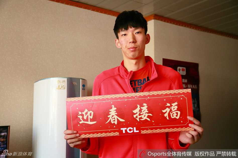 周琦身着白色训练服，面对镜头露出标志性的腼腆笑容，他双手抱拳向小球迷作揖拜年，眼神中满是大哥哥般的温柔与亲切。