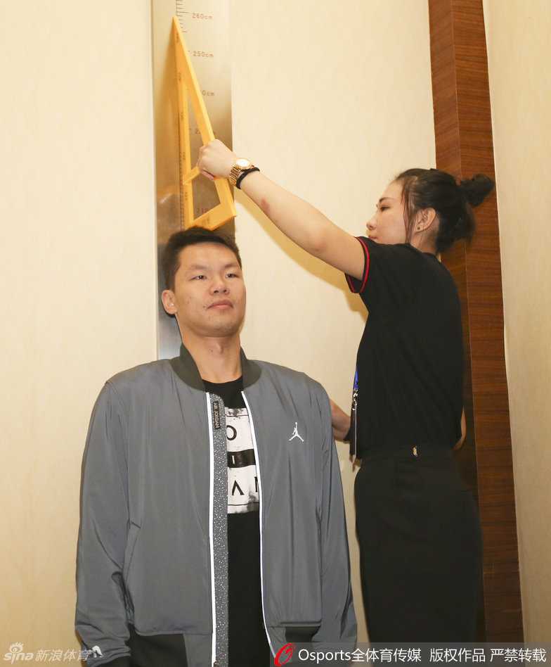 只见朱芳雨一脸轻松地站上身高测量仪，旁边的队友和工作人员正目不转睛地盯着缓缓下降的横杆。