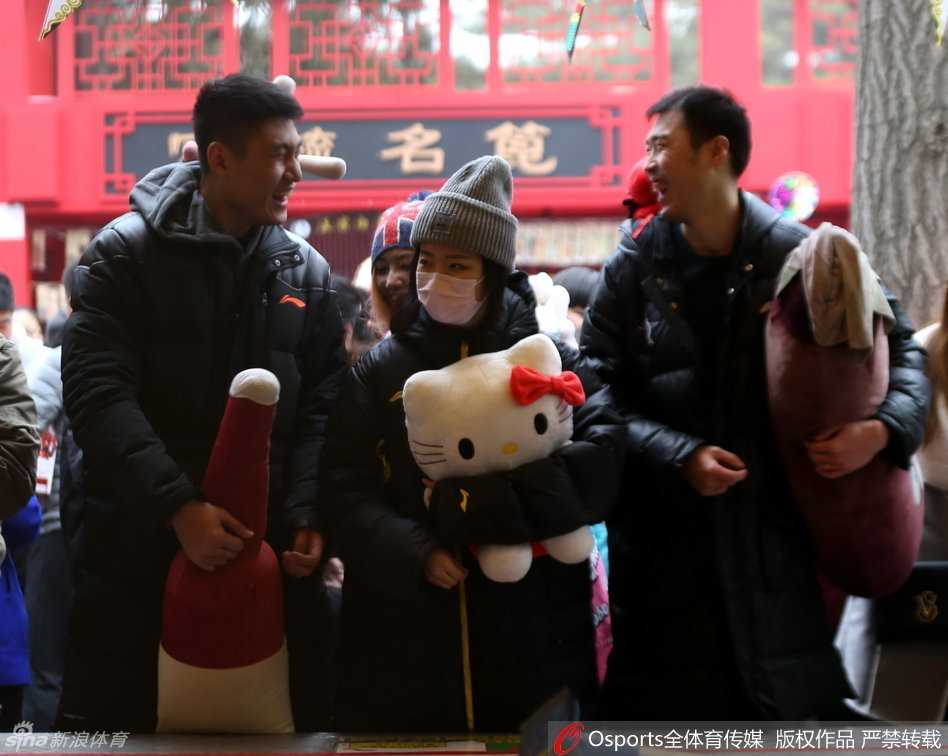 身着便装的篮球名将常林，在人声鼎沸的地坛庙会牌楼前驻足，脸上洋溢着节日的轻松笑容，与身边友人轻声交谈，仿佛暂时卸下了赛场上的所有压力。