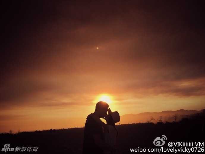 两人穿着印有卡通图案的白色情侣T恤，在充满生活气息的街角甜蜜牵手，李根低头看向妻子，眼神中满是宠溺与温柔。