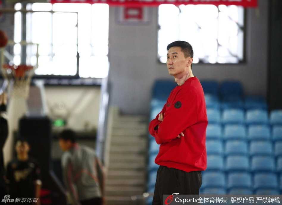杜锋双手抱胸站在场边注视球员训练，神情严肃而镇定，尽显名帅风范