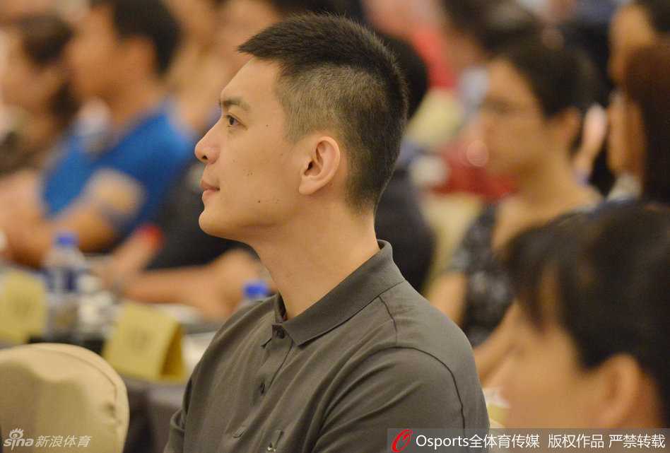 杨鸣在活动现场与学生互动，手指轻点桌面，神情专注地倾听孩子的提问。