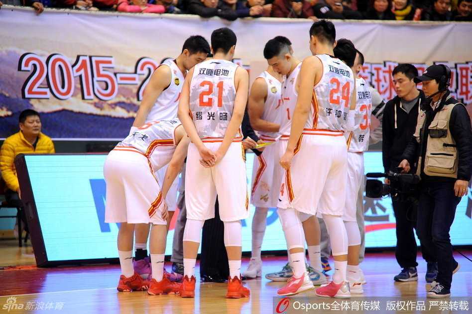 首发队员准备上场，五名先发球员神色凛然地站在中圈附近，他们身后巨大的八一军旗图案仿佛在燃烧，映照着勇士们无畏的脸庞。